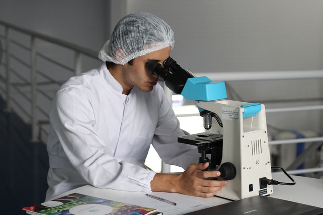 Scientist in laboratory analyzes scientific material using a microscope 