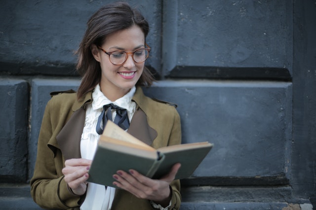 Cheerful female scholar reads an academic manuscript outdoors 