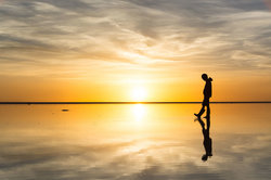 Academic strolls along the beach at sunset